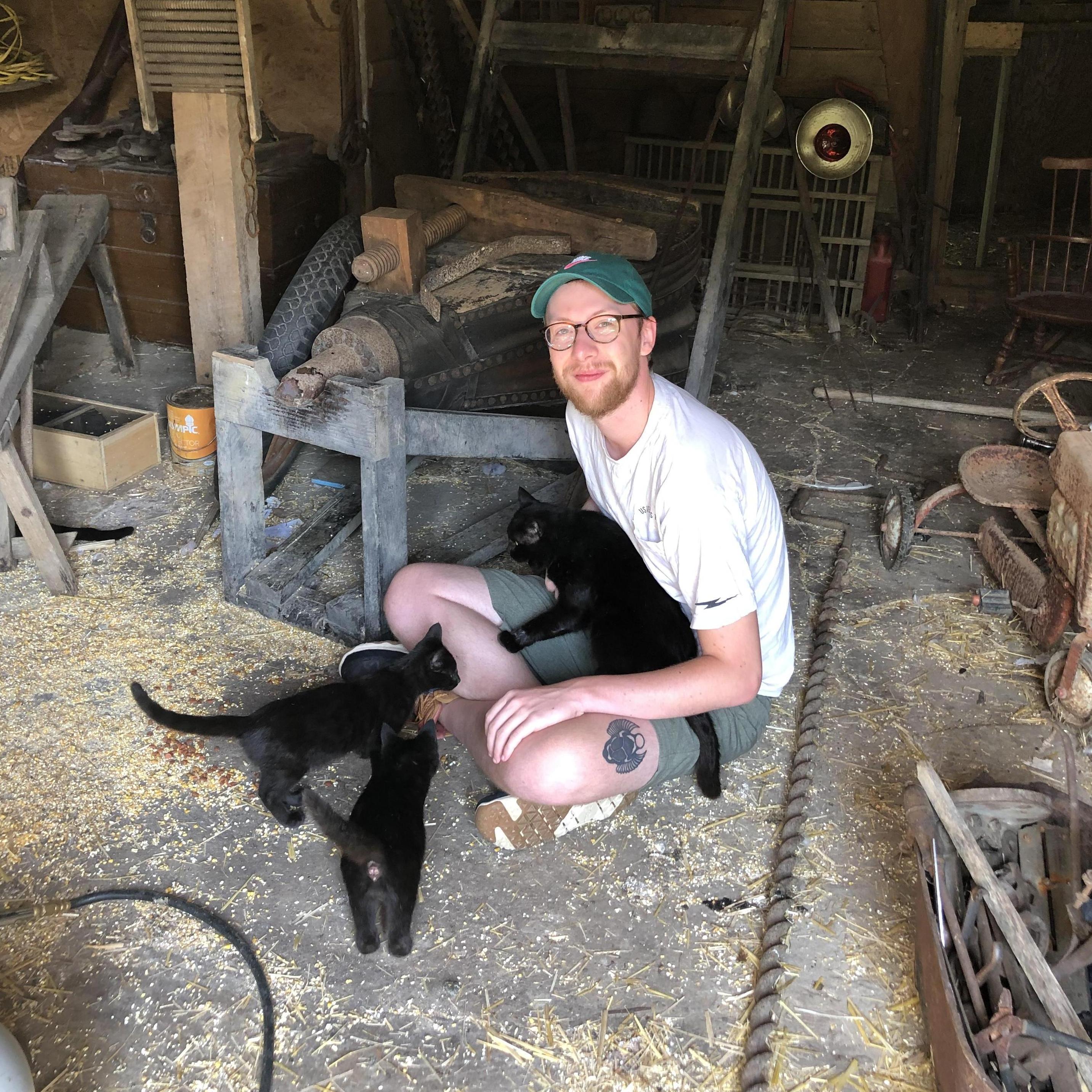 Nate in Ghent, WV surrounded  by barn cats. This was the trip that made us 100% afraid of spiders.
