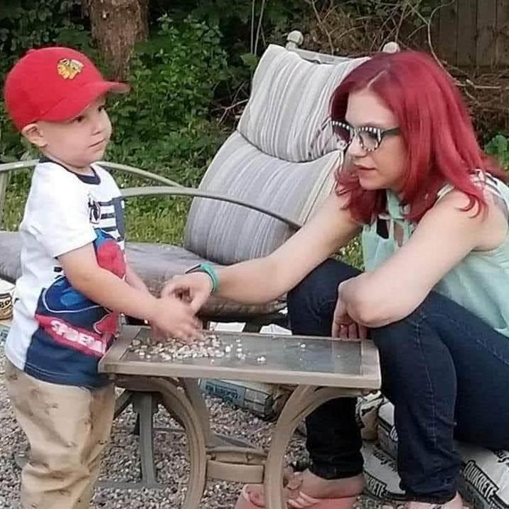 Alyssa and Connor playing with pebbles in the fire pit in Dana's backyard