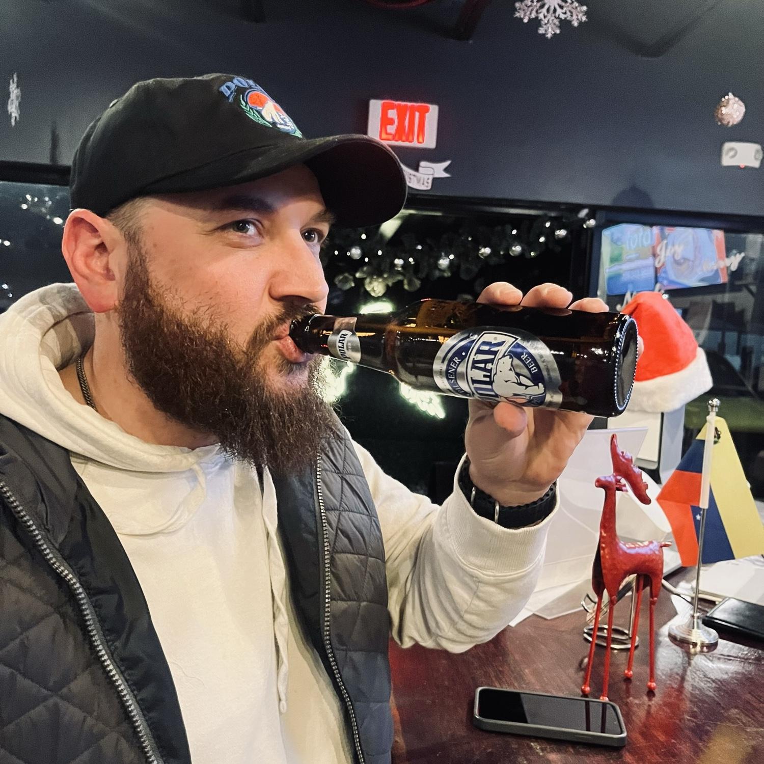 Alex drinking a polar beer wearing a polar hat in a Venezuelan restaurant in Charlotte!