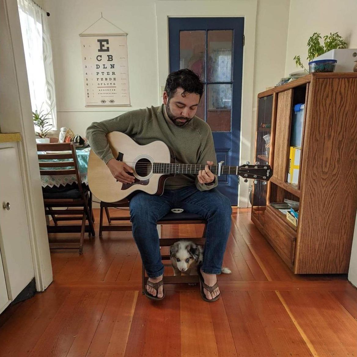 Oslo is helping Bino play guitar from under the chair