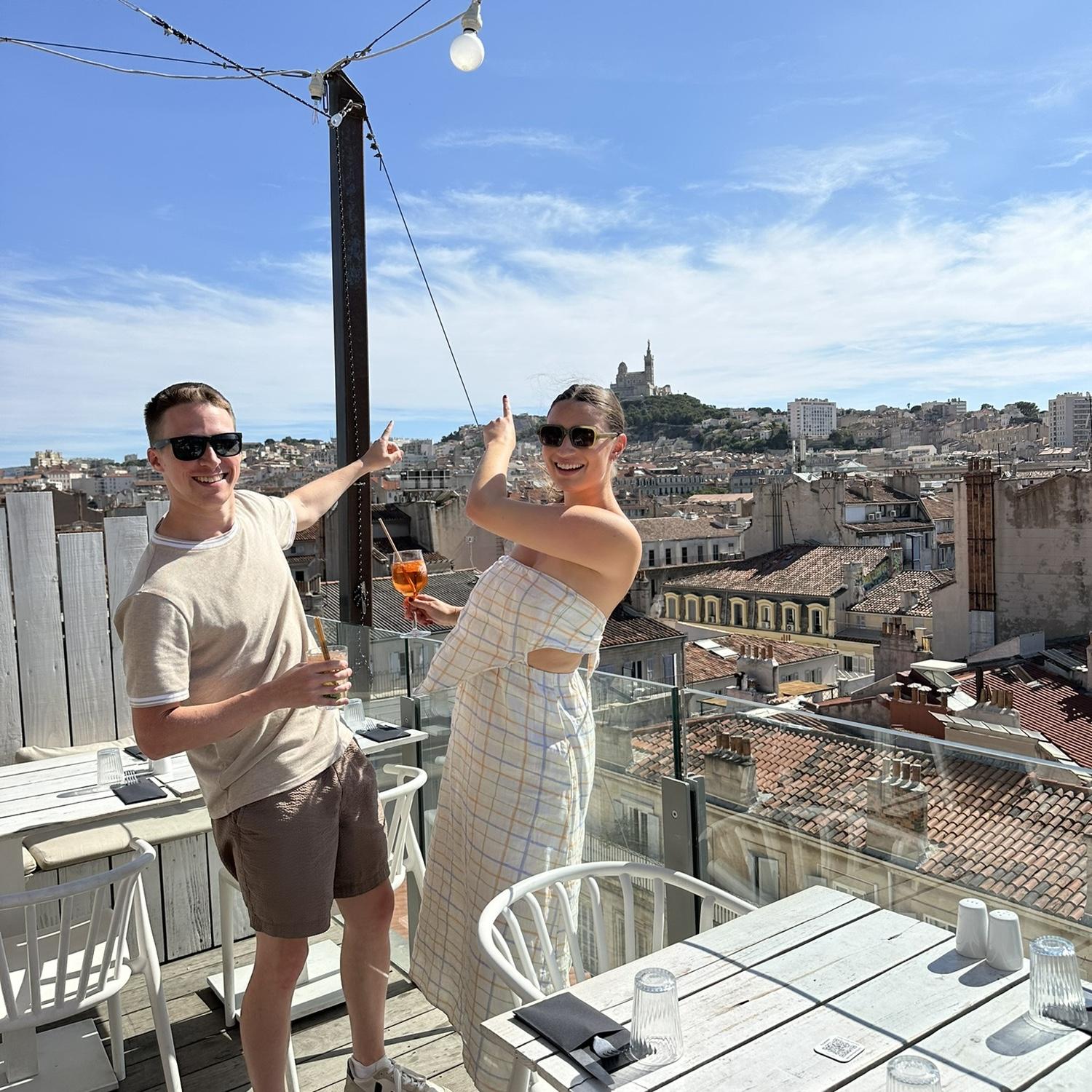 O & K having celebratory drinks at a rooftop bar with a great view of the proposal spot—yes, they walked all the way up and down from that point!