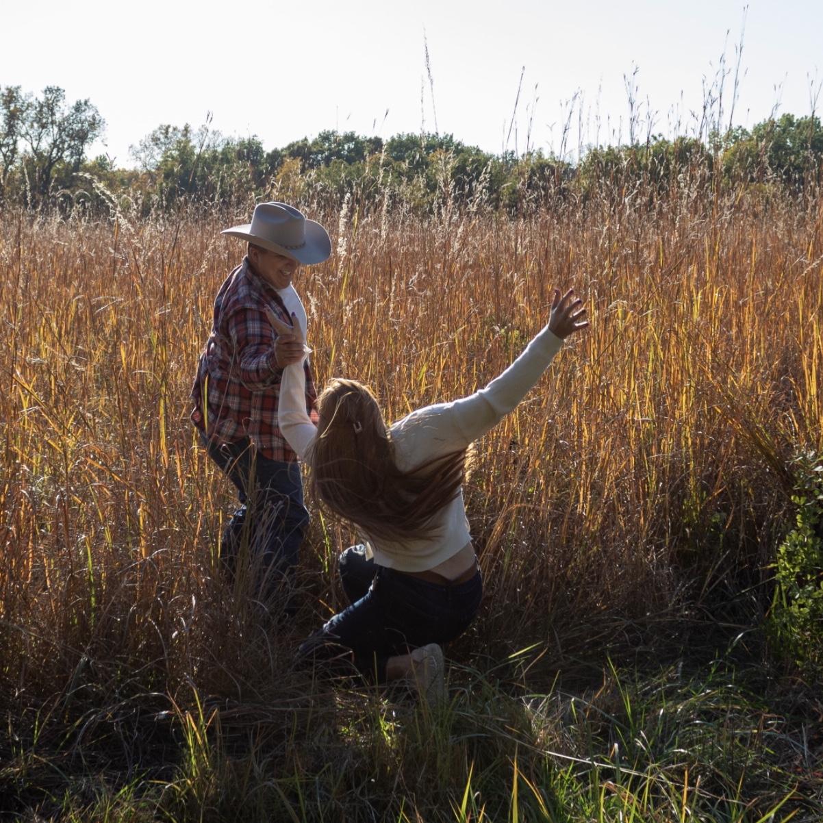 Chad pulling Emma into wheat field and making her fall.