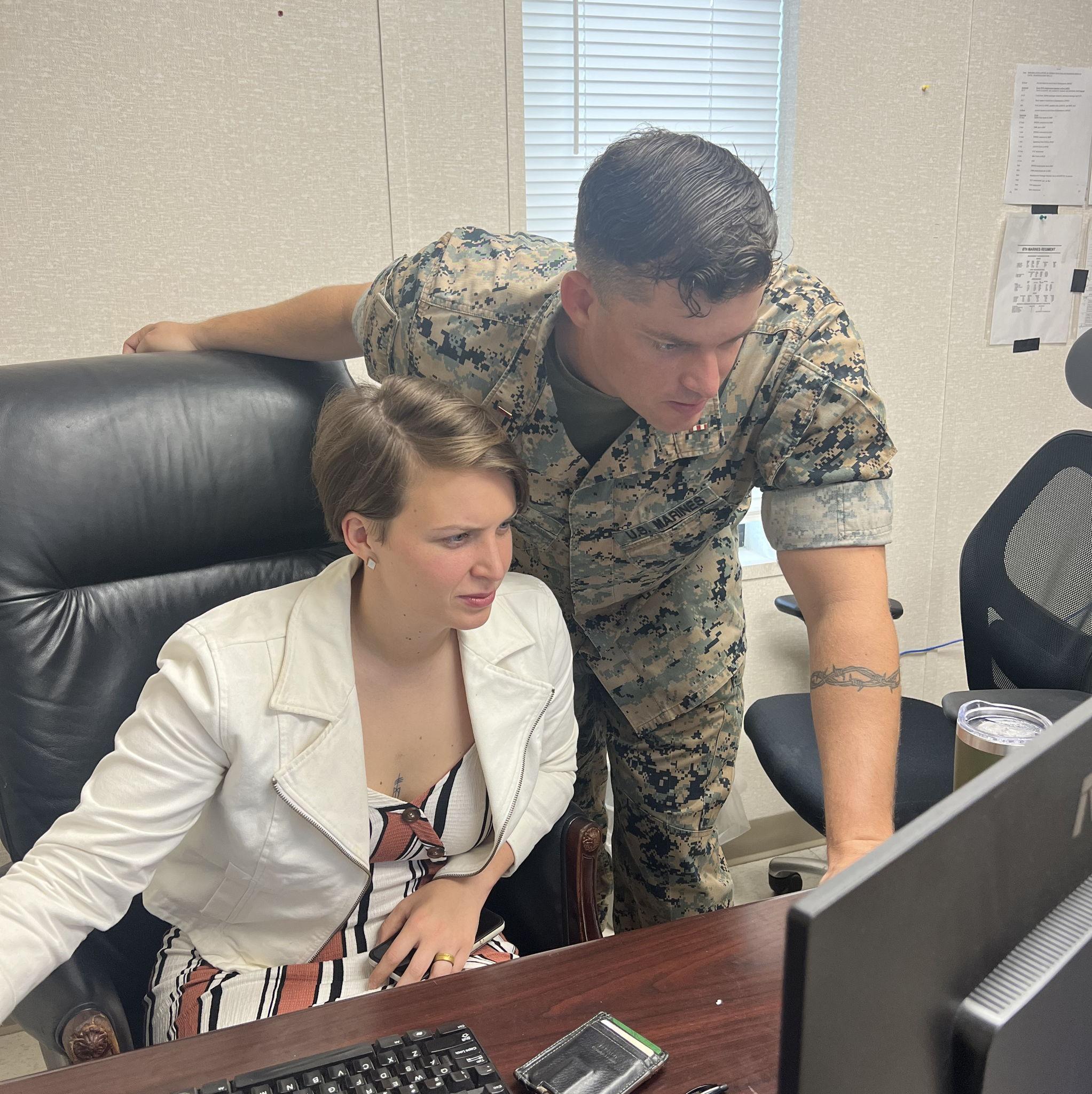 A Lieutenant teaching a newly promoted CWO2 how to use a system.
