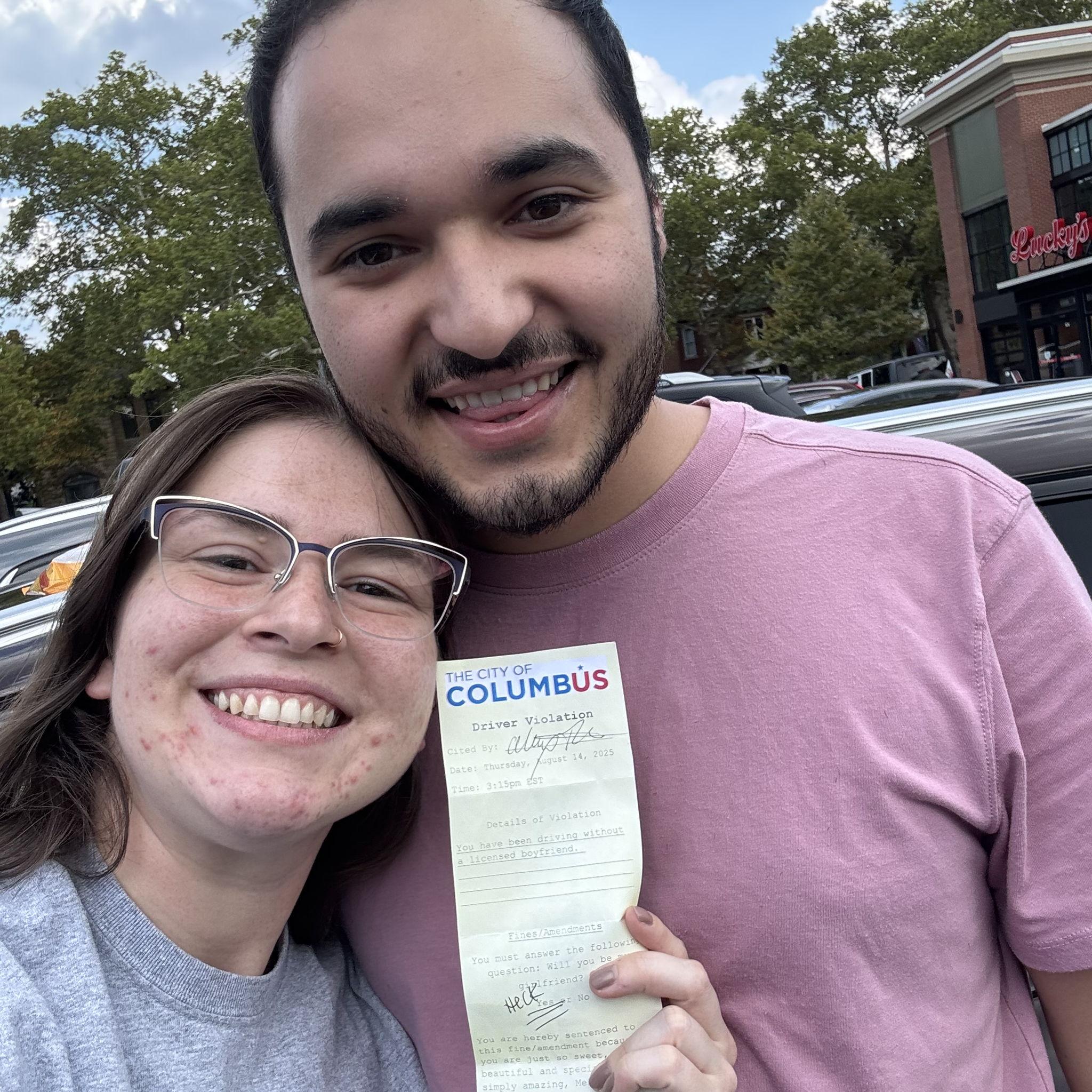 Alex asked Melissa to be his girlfriend with a little prank. He put a fake parking ticket on her car fining her for driving without a licensed boyfriend. She accepted the fine with a "heck yes".