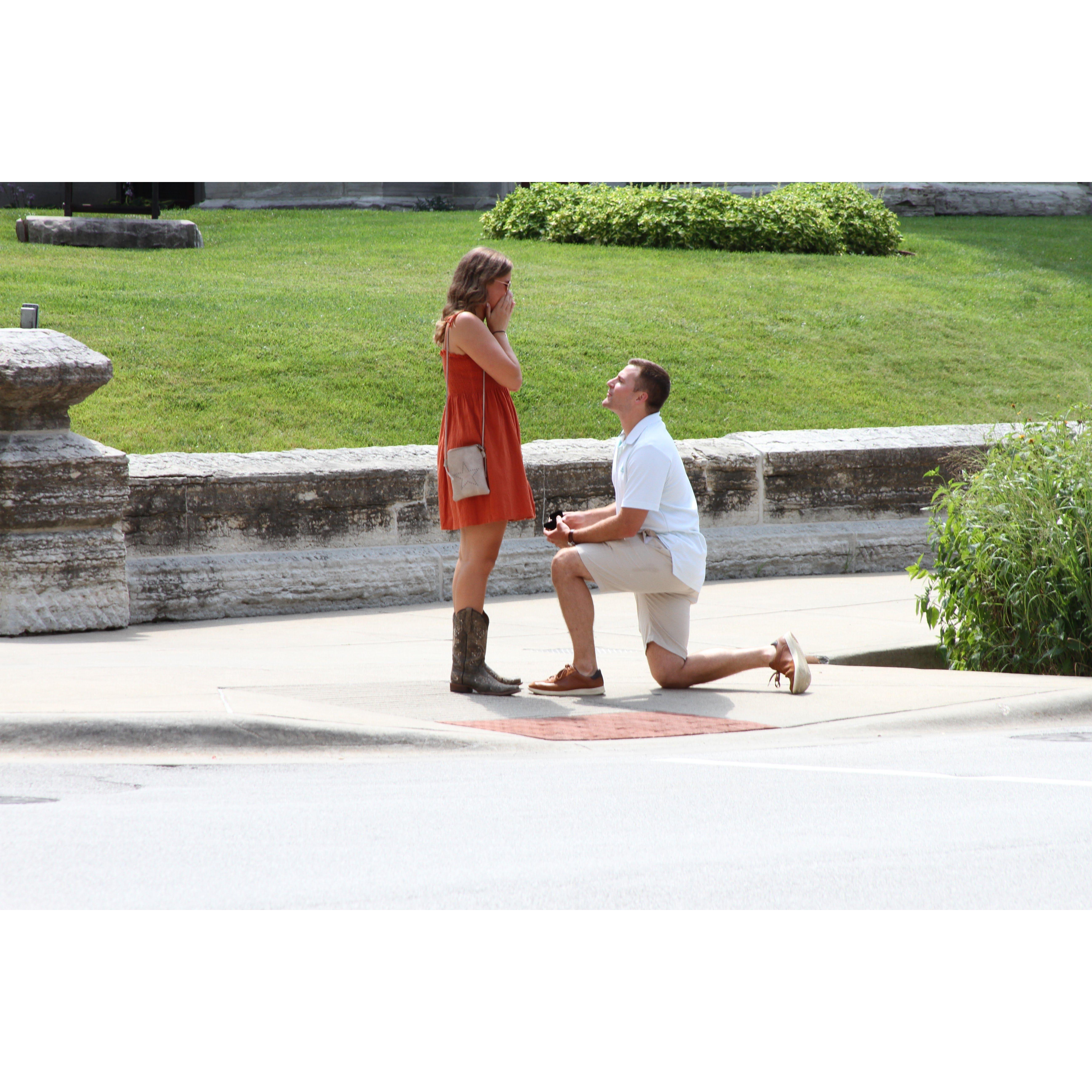 The surprise proposal! Story time: Matt told Steph they were meeting up w/ Sarah & Drake for lunch before Steph's "graduation party". On the walk there, Matt stopped & got down on 1 knee!