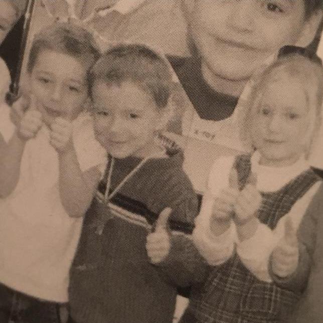 Broderick and Sarah (separated by a classmate) giving 'thumbs up' in kindergarten together