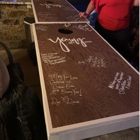 Words of love and support displayed on custom cornhole game boards made for the Young couple!