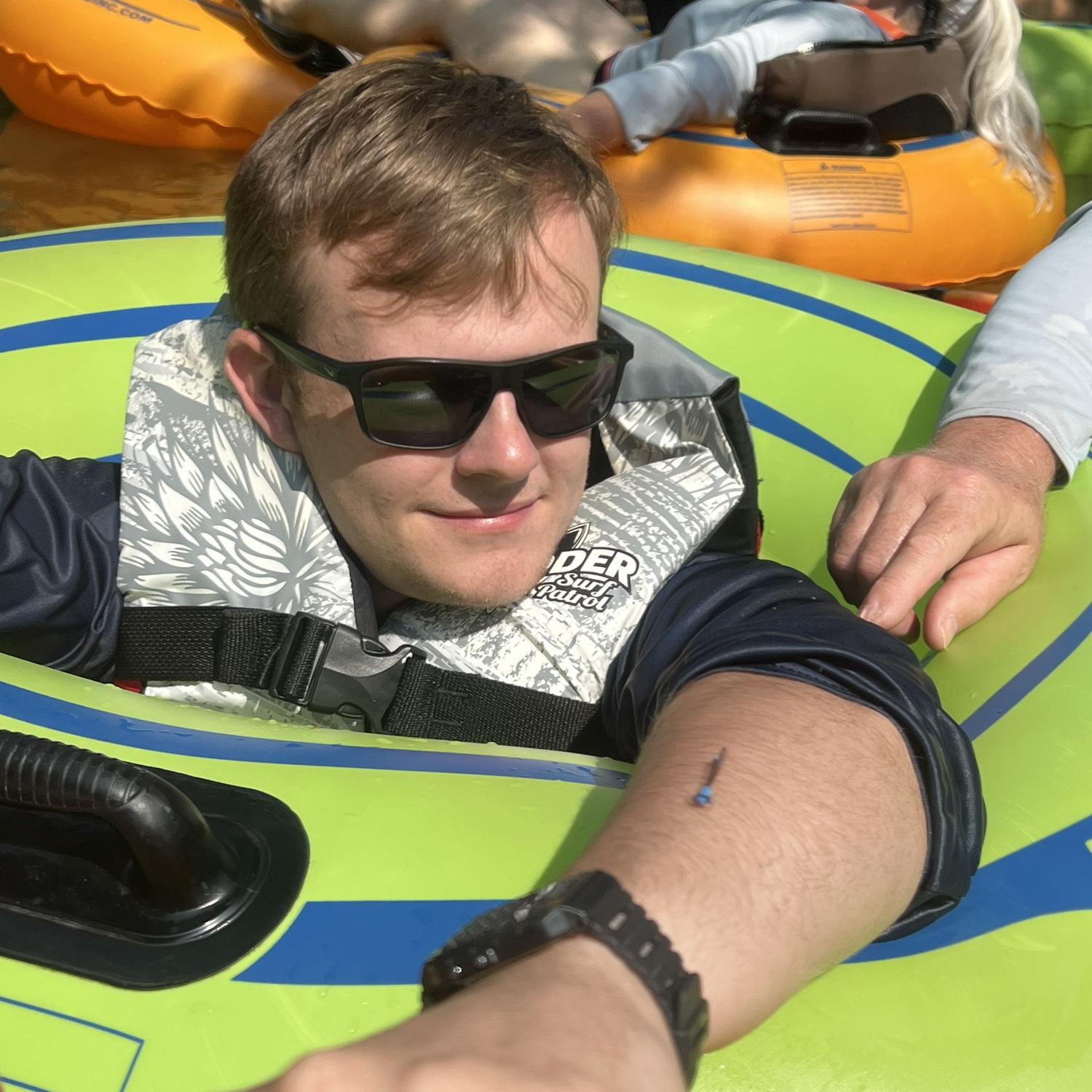 Zach lovingly staring at a dragonfly while tubing down a river.