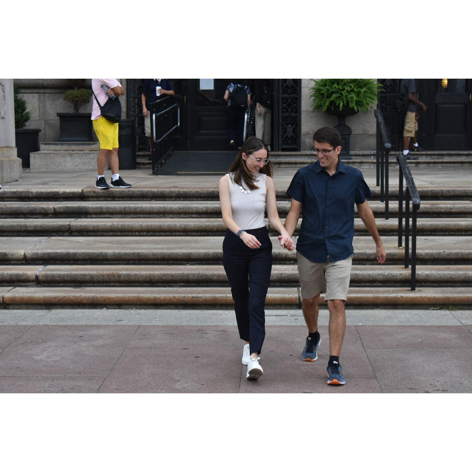 Fiancés walk hand-in-hand out of the library and into downtown Boston to begin their engaged life.