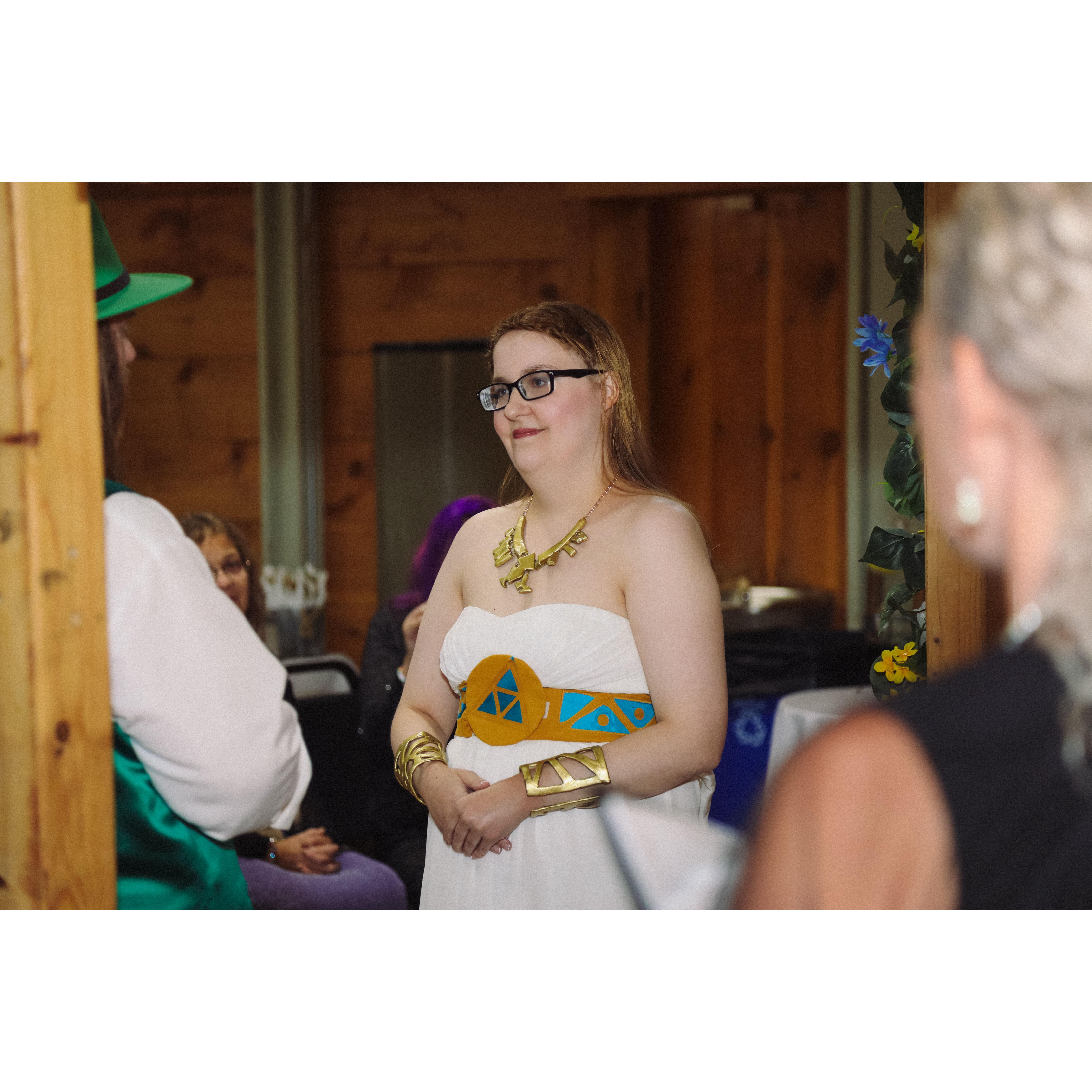 during the ceremony, Sara and Herb under the arch with the officiant vieved from behind Herb