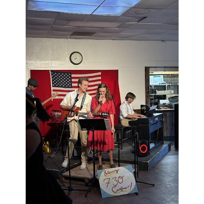 Lizzy singing for Joe's band at a school dance. Joe is playing the guitar he would borrow from Lizzy freshman year to have an excuse to chat with her more