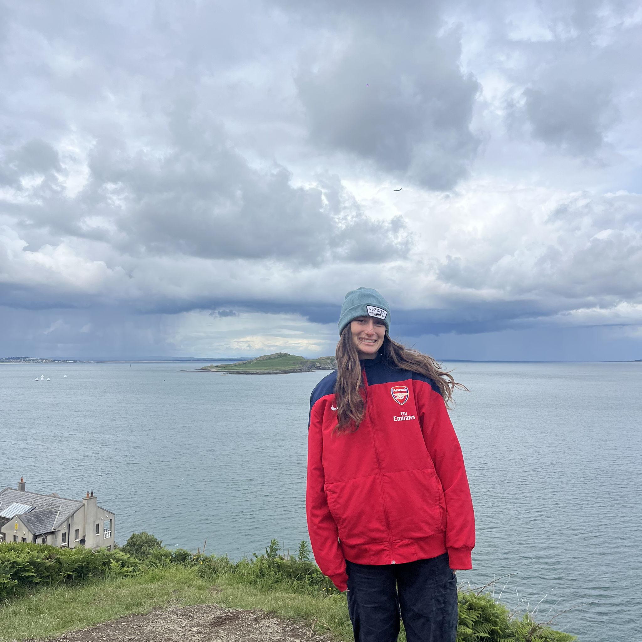 Charlotte standing on the edge of Howth, wearing the jacket of the best team in the world.