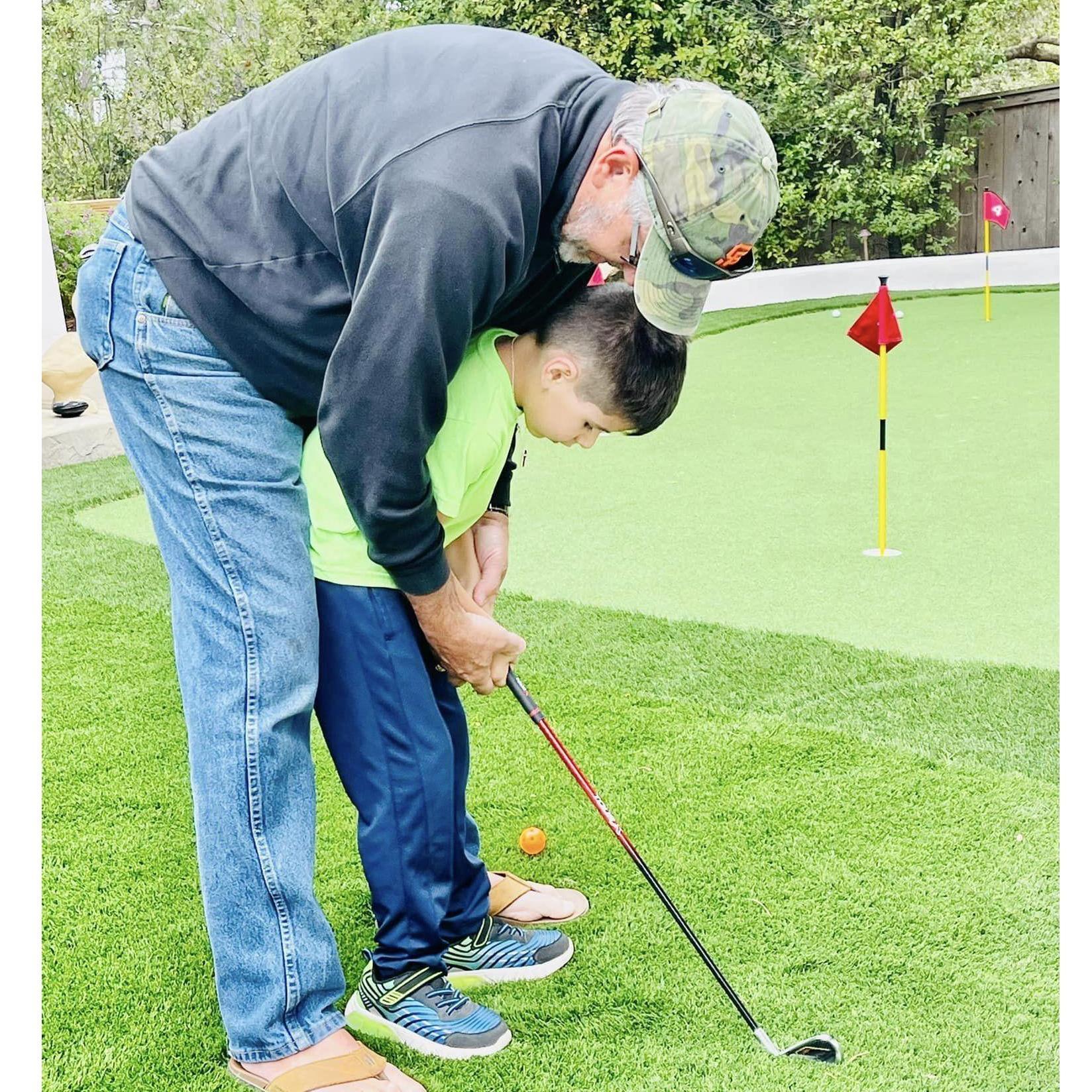 Grandpa giving Desmond putting lessons