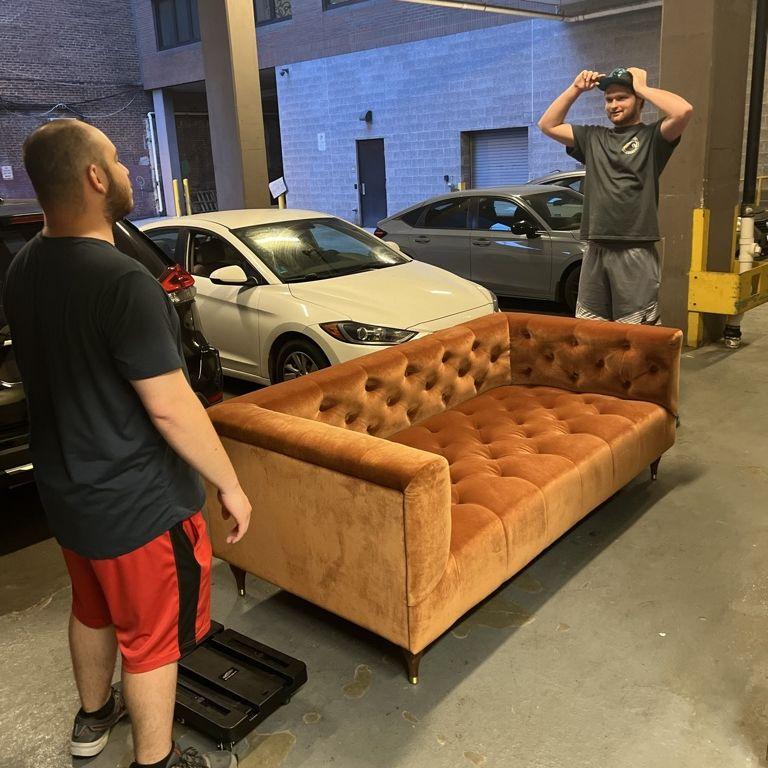 Jorge and Eric carrying Catie's new couch through the streets of DC into her apartment