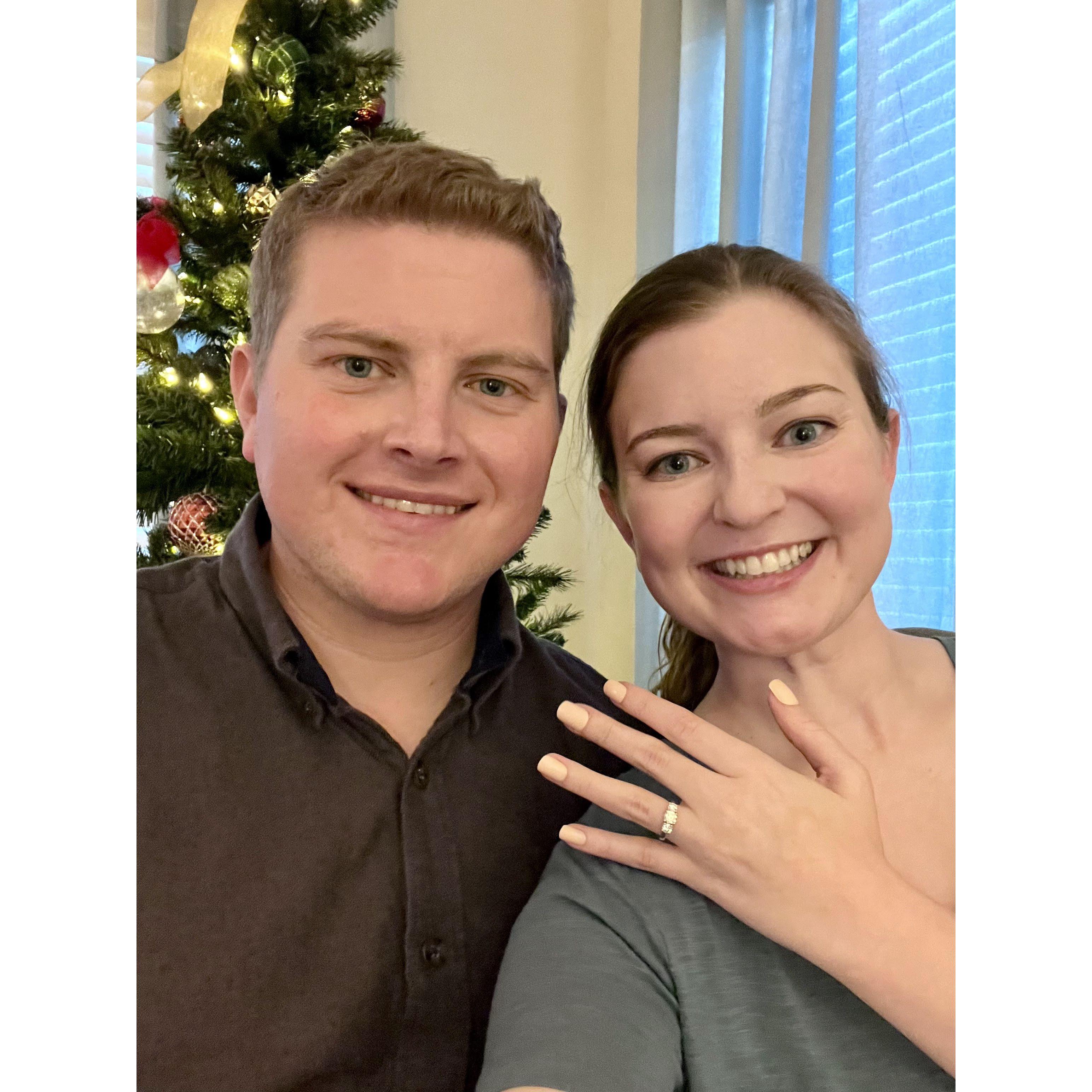 Kevin proposed to Caroline at her apartment as they were decorating for Christmas. He presented Caroline with a custom ornament to commemorate their engagement before getting down on one knee!