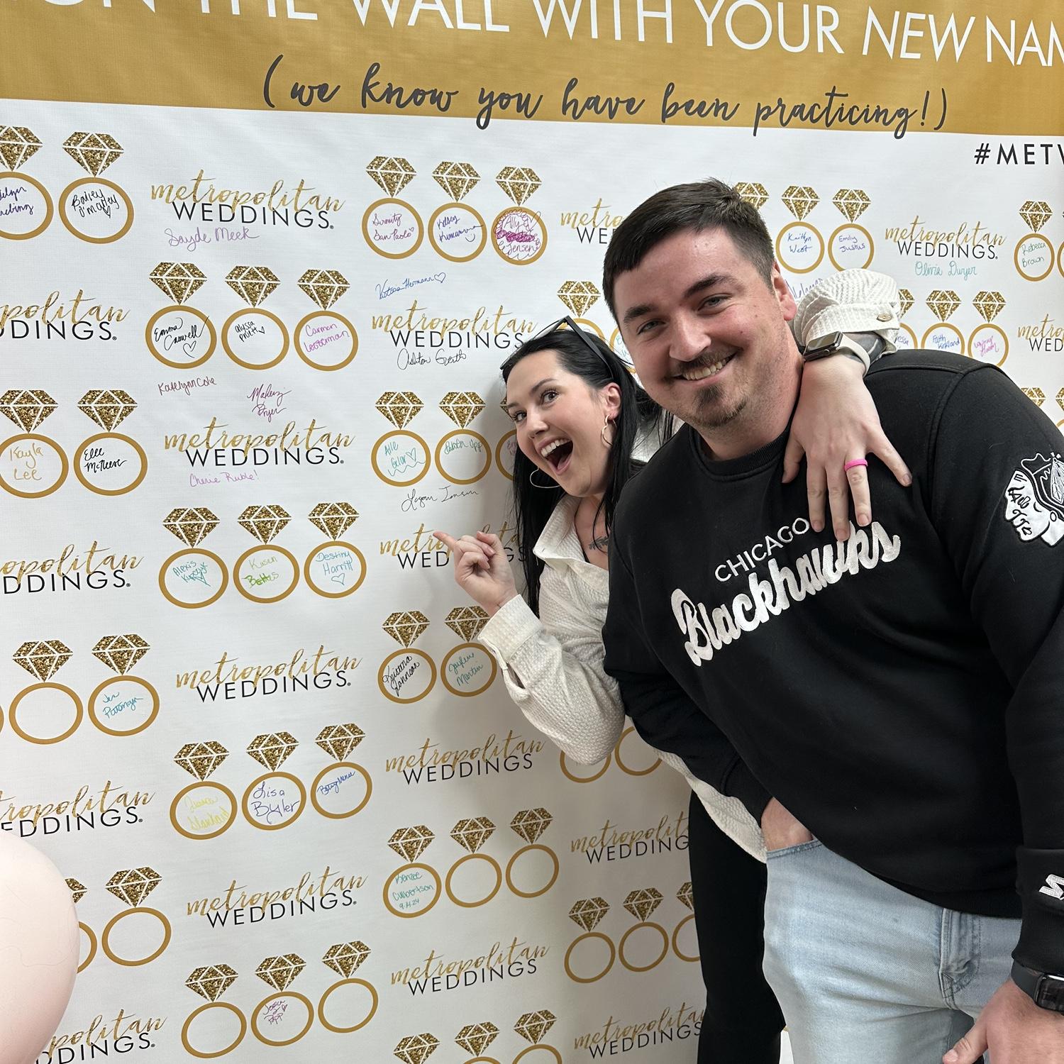 No time to waste! We visited the bridal expo in January 2024. Here's a photo of us having just signed my future last name! (Still working on cursive J's)