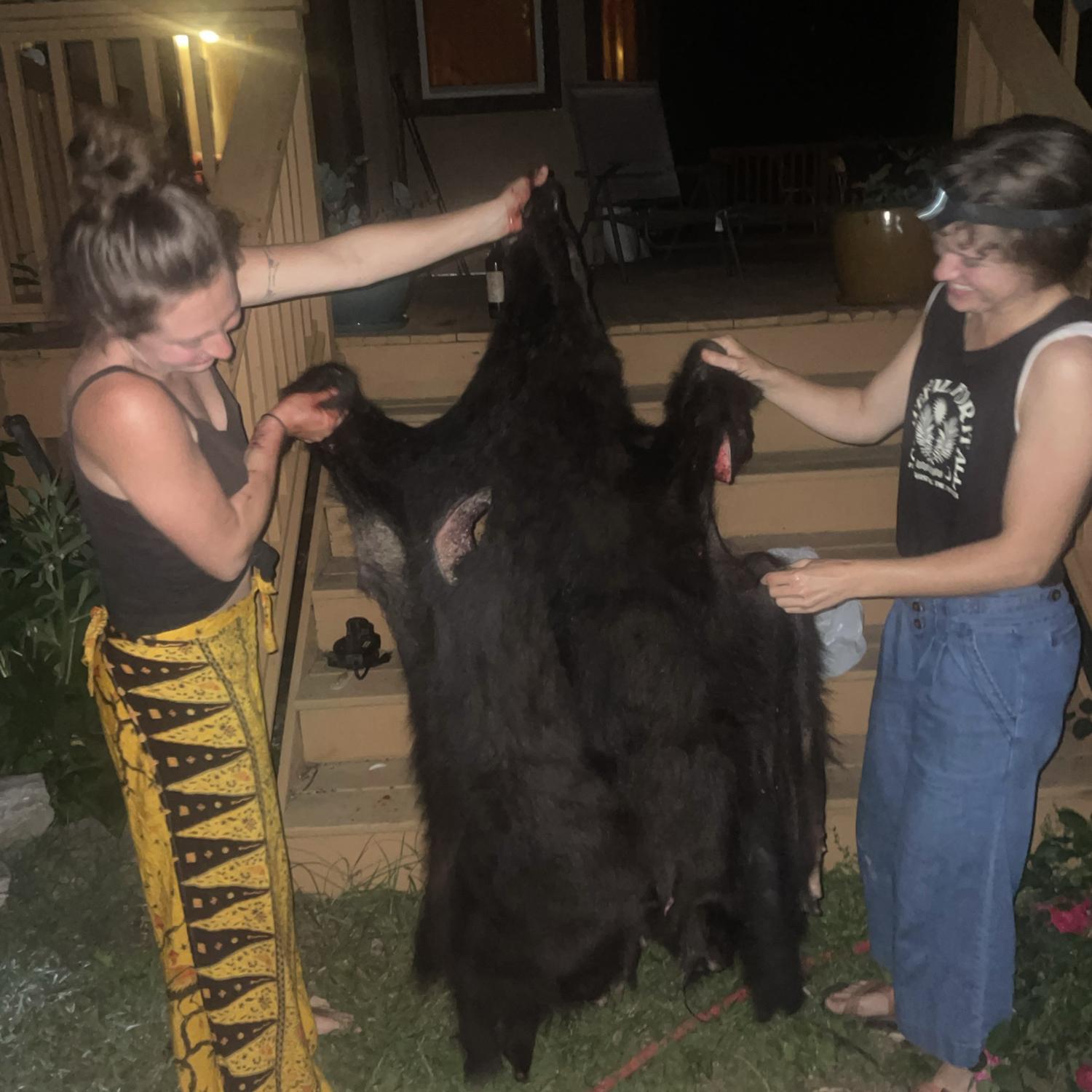 Megan and Lucille holding up the bear pelt they processed with Morgan and Thomas. (Morgan picked up a roadkill bear in the back of her car— it’s a good story).