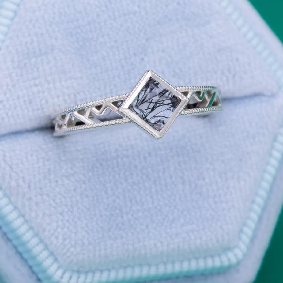 The ring Francis designed for Alex. The center stone is Tourmalinated Quartz, and the design features the mountains that Alex loved seeing in the window of our first apartment together.