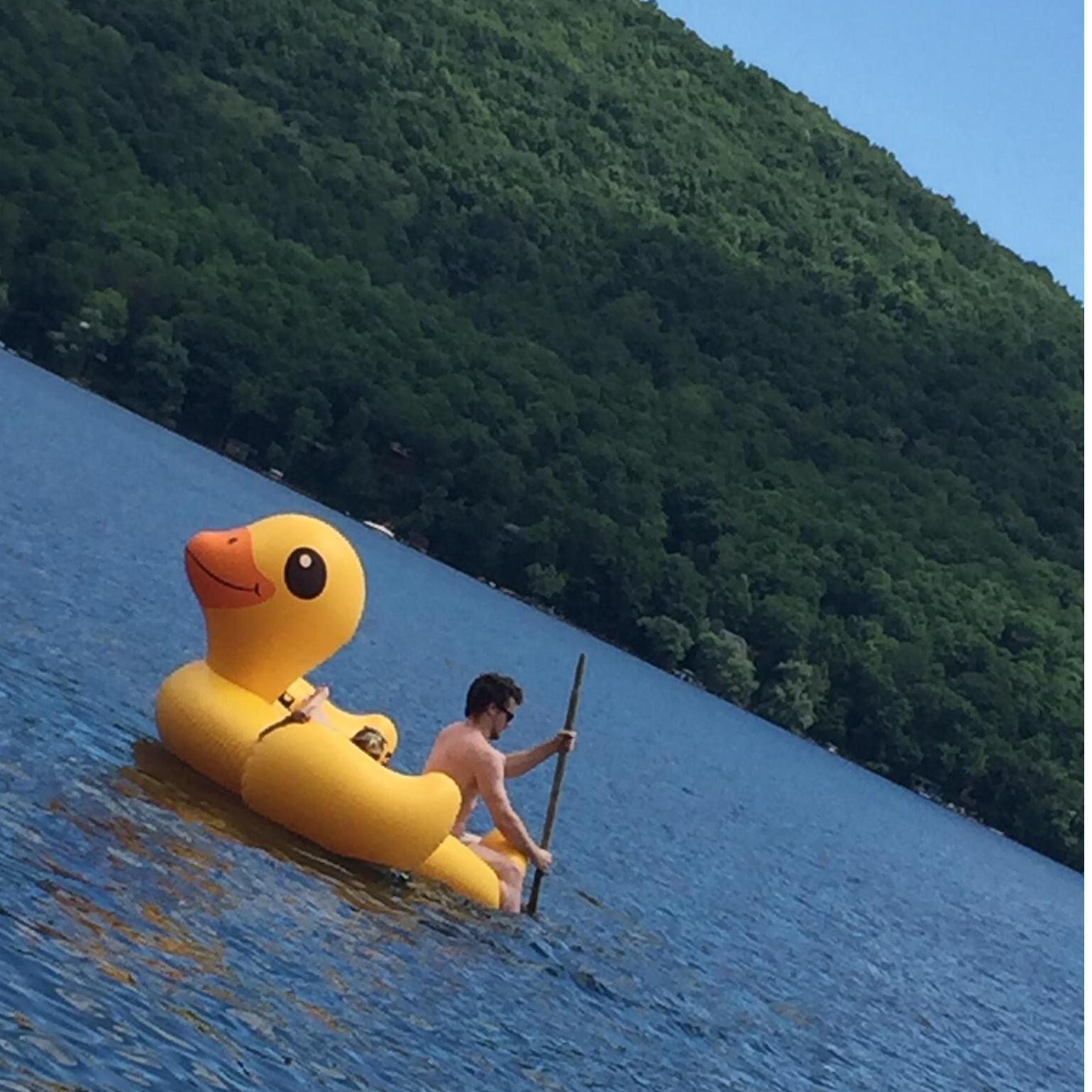 Ray rowing Emily around on a giant rubber ducky during a Bales family vacation in Upstate New York.